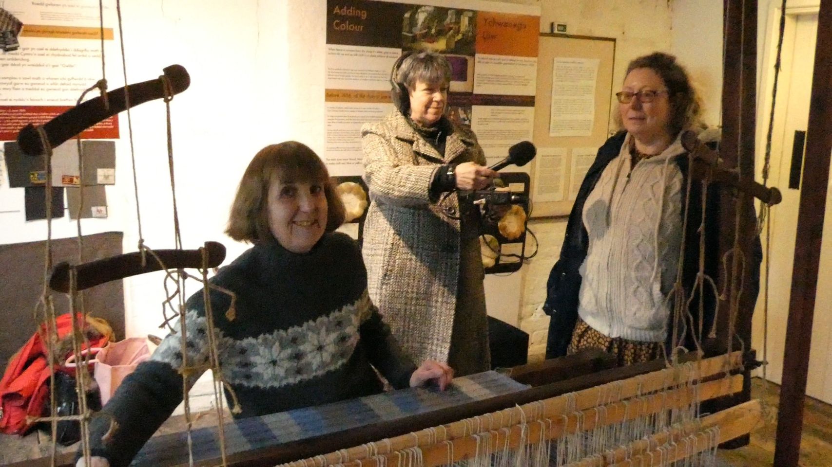 Cast and crew filming by a loom